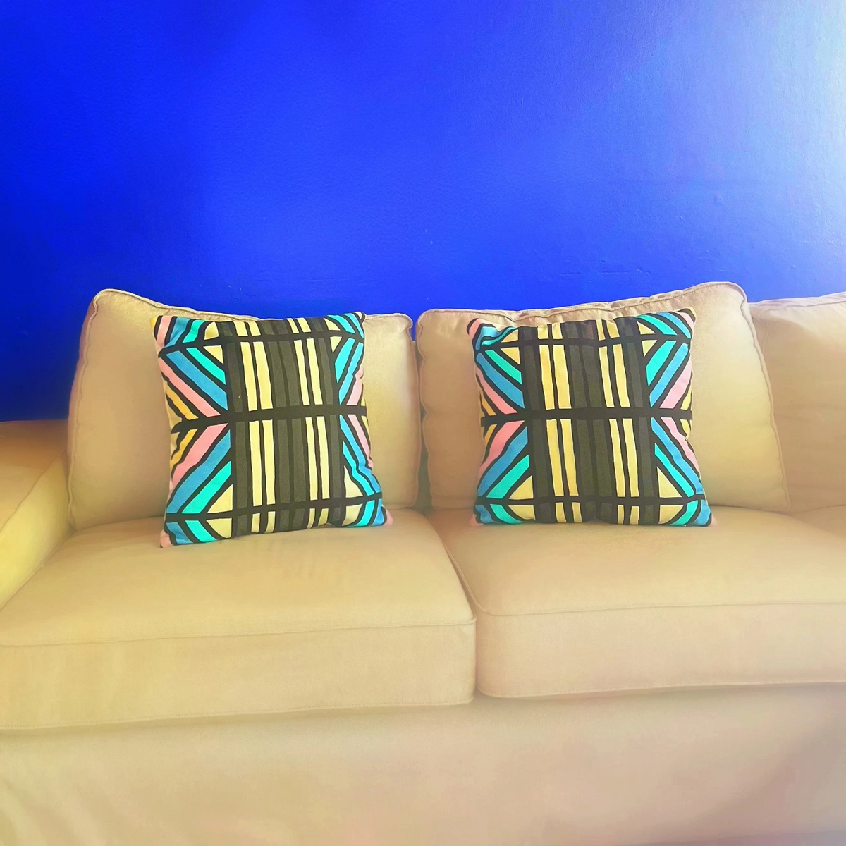 Two HD Decor Show Me A Good Time standard pillowcases with turquoise, lavender, and black geometric patterns on a sofa
